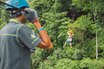 Full length of woman zip lining in forest