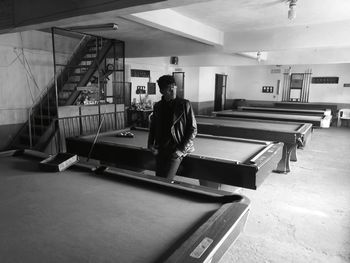 Man standing amidst pool tables