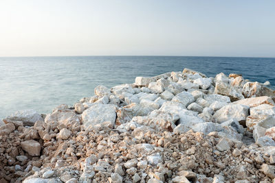 Rocks by sea against clear sky