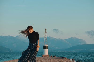 Woman standing by sea against sky