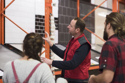 Salesman assisting couple in choosing tile at hardware store