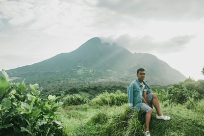 Portrait of young man on mountain against sky