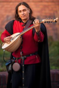 Portrait of smiling man playing musical equipment while standing outdoors