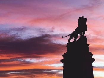 Silhouette of statue against cloudy sky during sunset