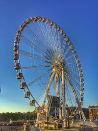 Low angle view of ferris wheel against blue sky