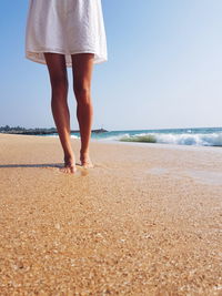 Low section of woman standing on shore at beach