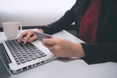 Midsection of man using laptop on table