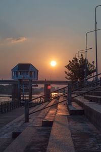 Street by sea against sky during sunset