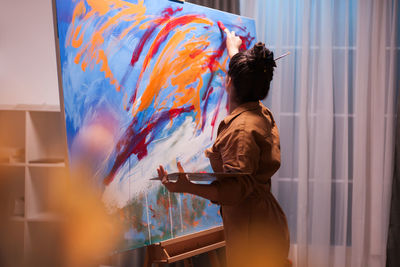 Rear view of woman standing against multi colored wall