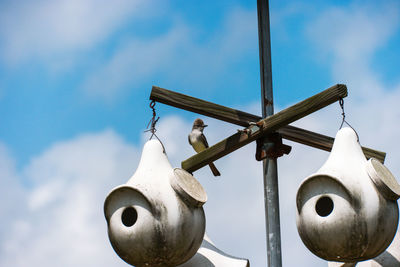Low angle view of bird perching on birdhouse against sky