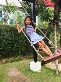 Portrait of smiling girl swinging in park