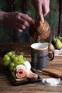 Cheese plate with goat cheese, grapes and figs, copper teapot, angle view