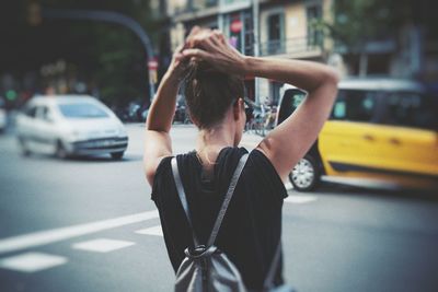 Rear view of woman with umbrella on street in city