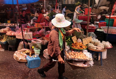 Vendor carrying baskets on shoulder at market