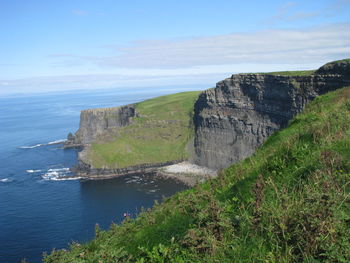 Scenic view of sea by cliff against sky