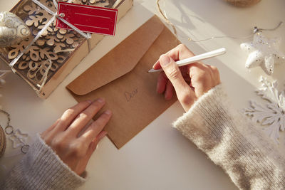 Female hand signs a festive envelope. preparing for the christmas holidays. christmas decorations 