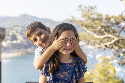 Portrait of boy covering sister eyes outdoors