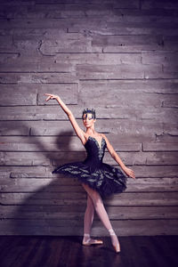 Ballet dancer dancing against wall