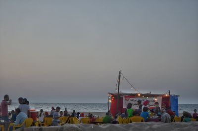 People at beach against clear sky