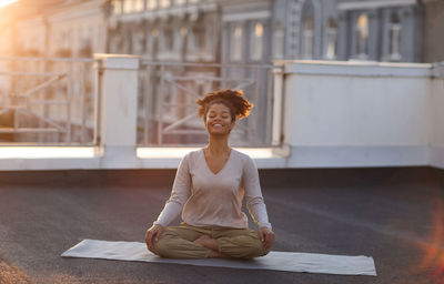 Portrait of young woman sitting on window