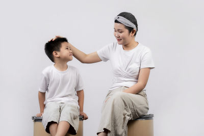 Boy looking away while sitting against white background