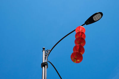 Low angle view of red umbrella against clear blue sky