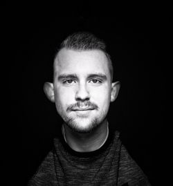 Portrait of young man against black background