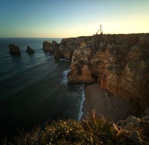 Rock formations by sea against clear sky