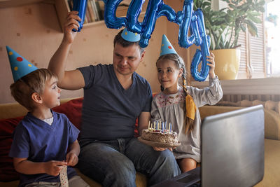 Cheerful father holding cake while siting with kids