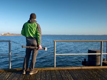 Hobby photograph with camera on tripod in hand. wooden board quay, sunny morning at sea. smooth sea