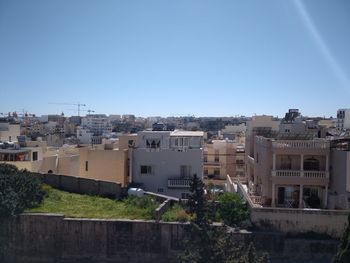 Buildings in city against clear blue sky