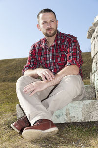 Man looking away while sitting against sky