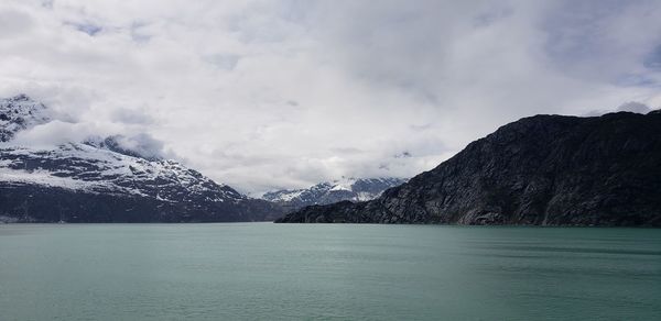 Scenic view of lake by snowcapped mountains against sky