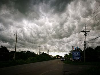 Low angle view of electricity pylon against cloudy sky