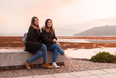 Portrait of women sitting on retaining wall