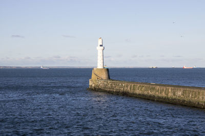 Lighthouse by sea against sky