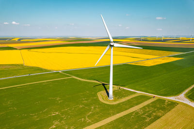 Aerial view of wind turbines farm on agricultural field in summer