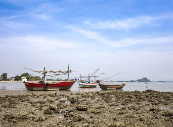 Fishing boats on beach against sky