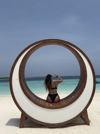 Low angle view from behind of woman in bikini on beach