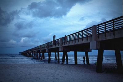 Pier on sea against cloudy sky