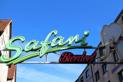 Low angle view of sign against blue sky