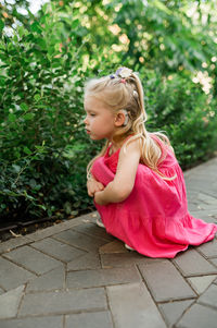 Side view of young woman sitting on footpath