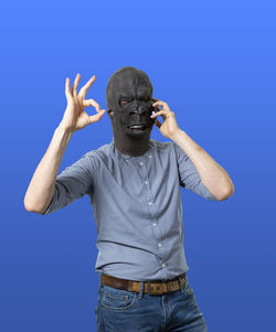 Portrait of man wearing mask against blue background