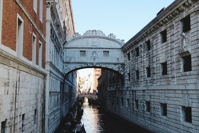 Arch bridge over canal amidst buildings against sky