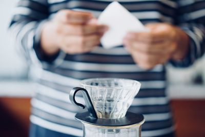 Midsection of woman preparing coffee on table at cafe