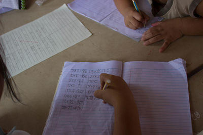 Cropped hands writing in paper at home