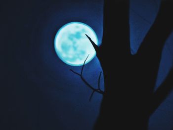 Close-up of silhouette hand holding moon at night