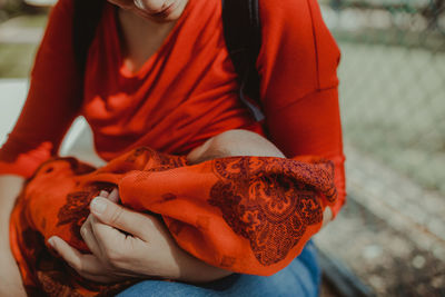 Midsection of woman breastfeeding baby outdoors