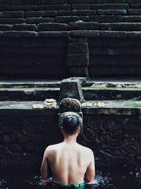 Rear view of shirtless man swimming in lake