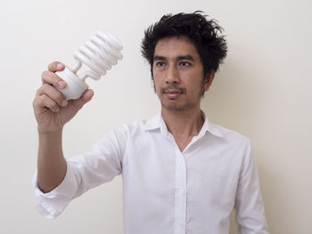 Portrait of young man standing against white background